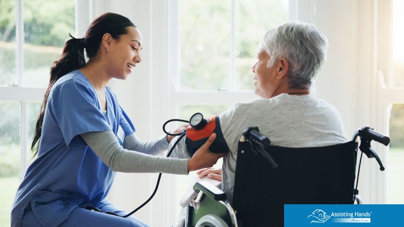 caregiver monitoring elderly woman's blood pressure who had fainted on the floor