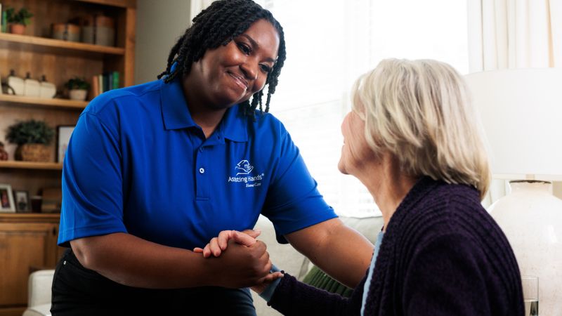 professional assisting hands caregiver with a senior woman at home