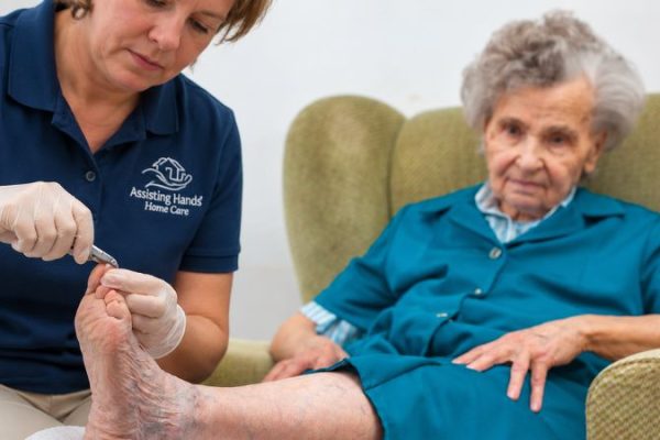 Assisting Hands Caregiver Cutting Senior Woman's Nails For Hygiene and Grooming