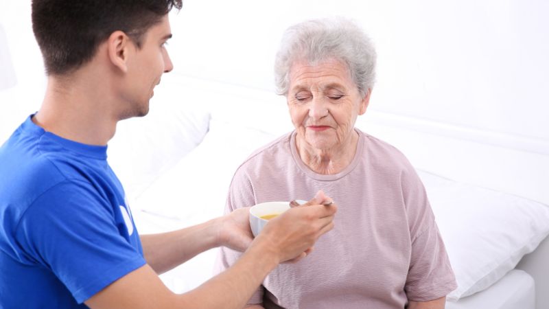 caregiver feeding senior woman nutritious soup