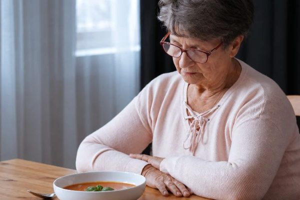 senior woman refusing to eat and staring at the meal