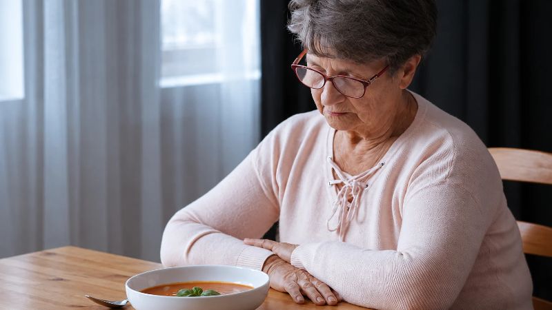senior woman refusing to eat and staring at the meal