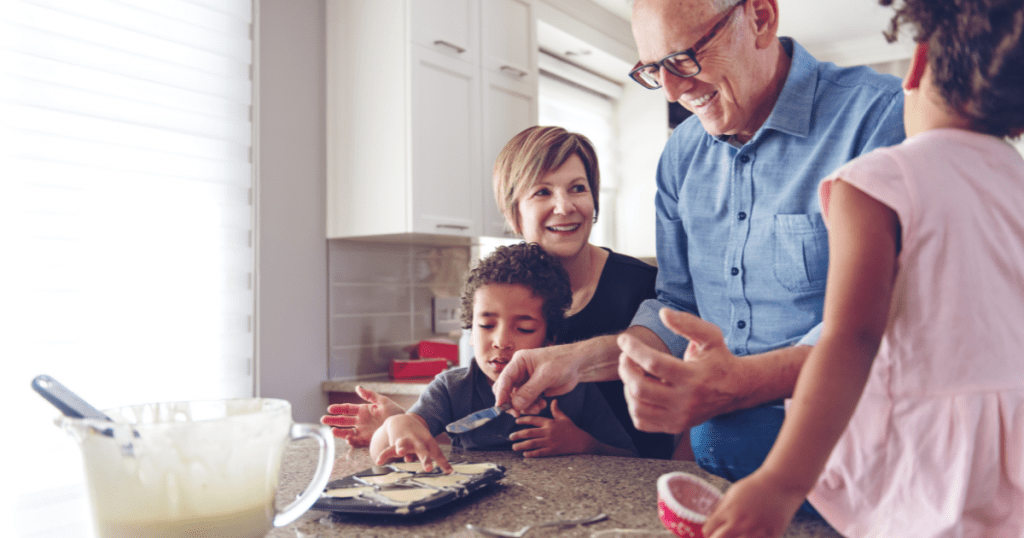Family caregiver assists her children and her elderly father make cookies during the holidays