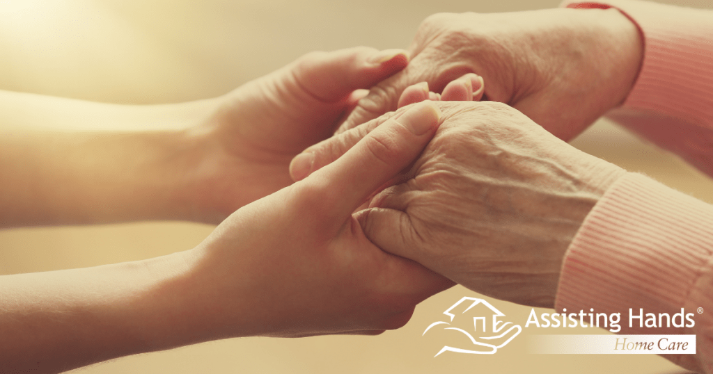 A caregiver holds hands with a senior, displaying empathy and concern, qualities agencies look for when hiring caregivers in Littleton