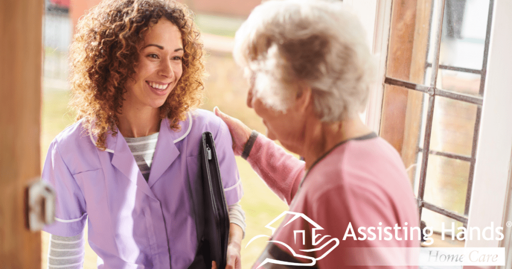 Smiling senior stands at the front door and welcomes a new caregiver into her home