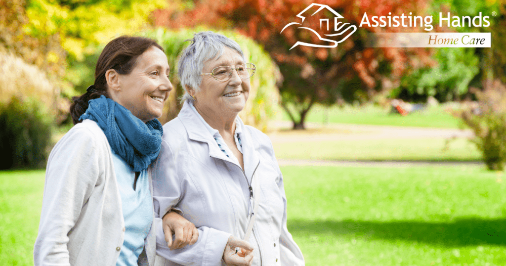 A recently retired woman enjoys her caregiving job as she walks with a senior client outside.