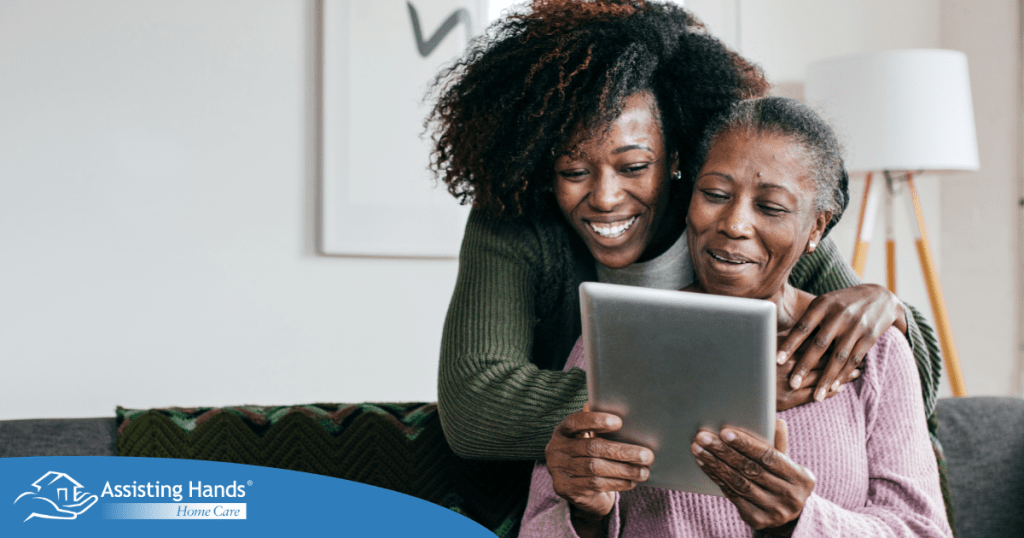 A caregiver helps a senior with her tablet, representing the rise of technology in home care.