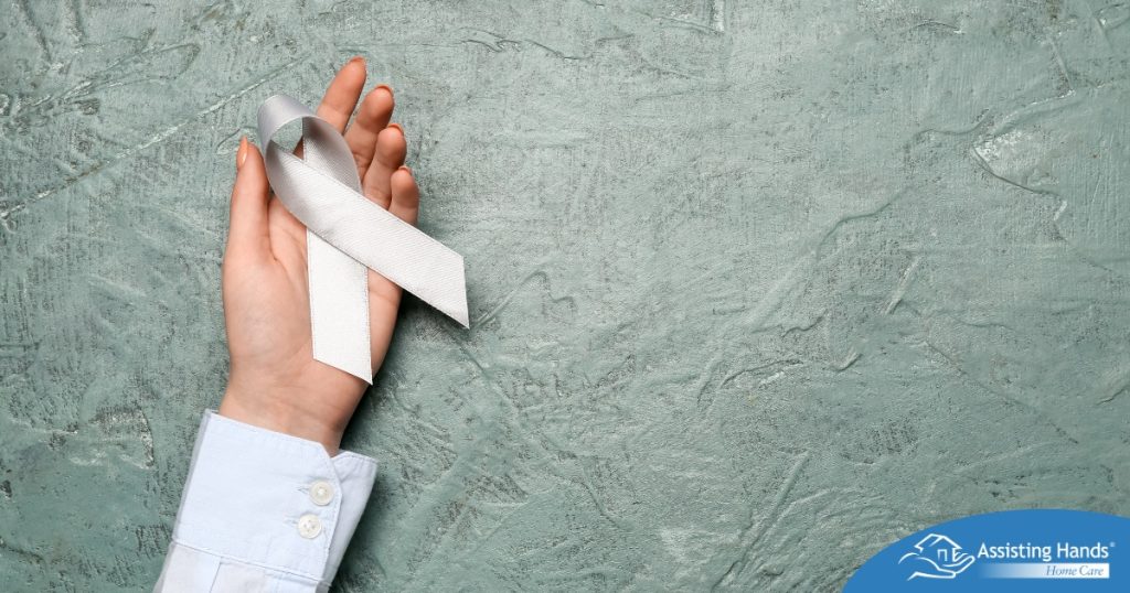 A woman holds a silver ribbon, representing Parkinson’s Awareness Month.