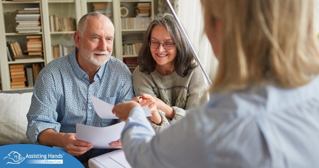 An older couple receives and considers papers from a woman, representing someone considering long-term care insurance.