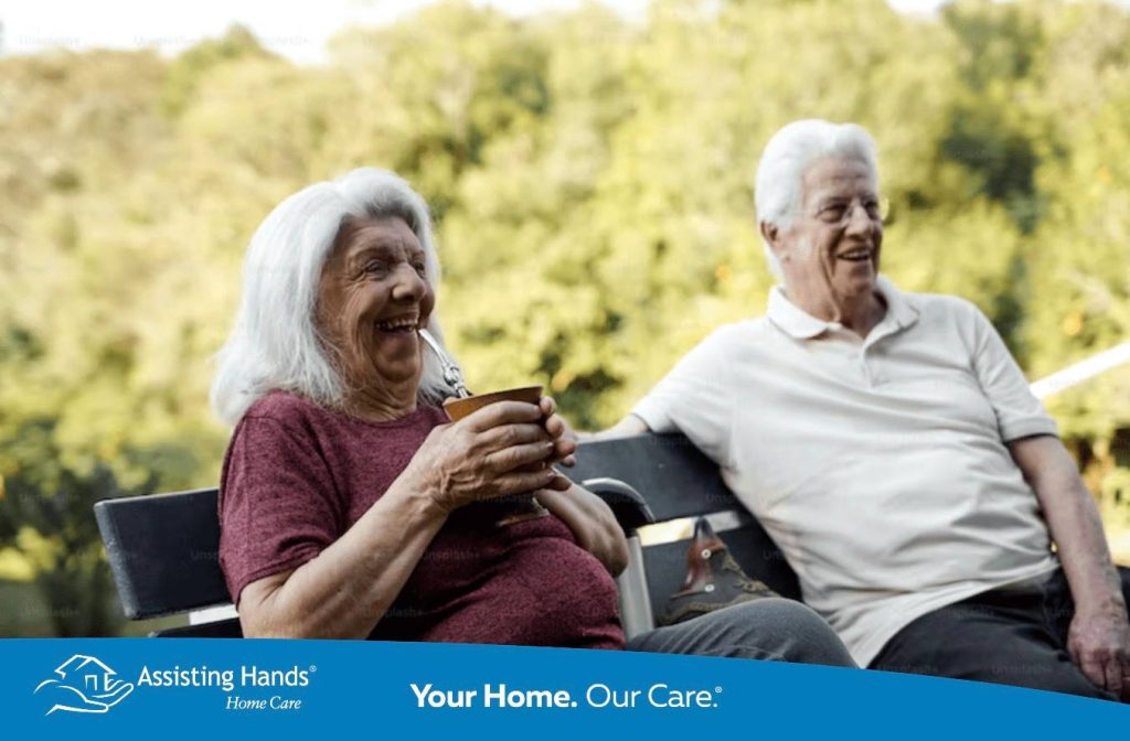 elderly woman drinking water sitting with an elderly man
