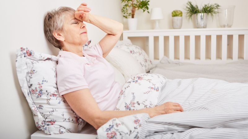 Senior Woman with Parkinson's Disease Lie on Bed