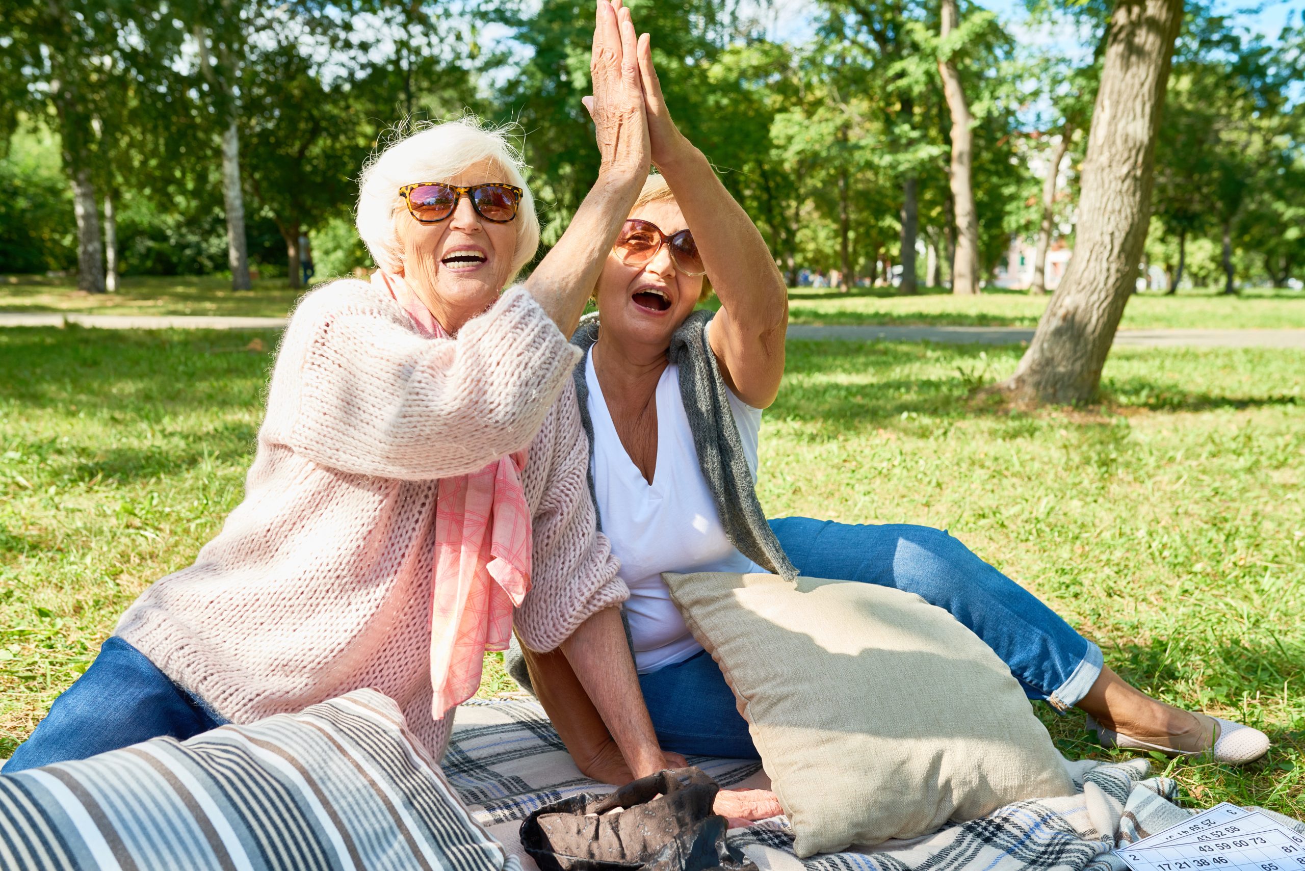 two female seniors high-fiving each other at park